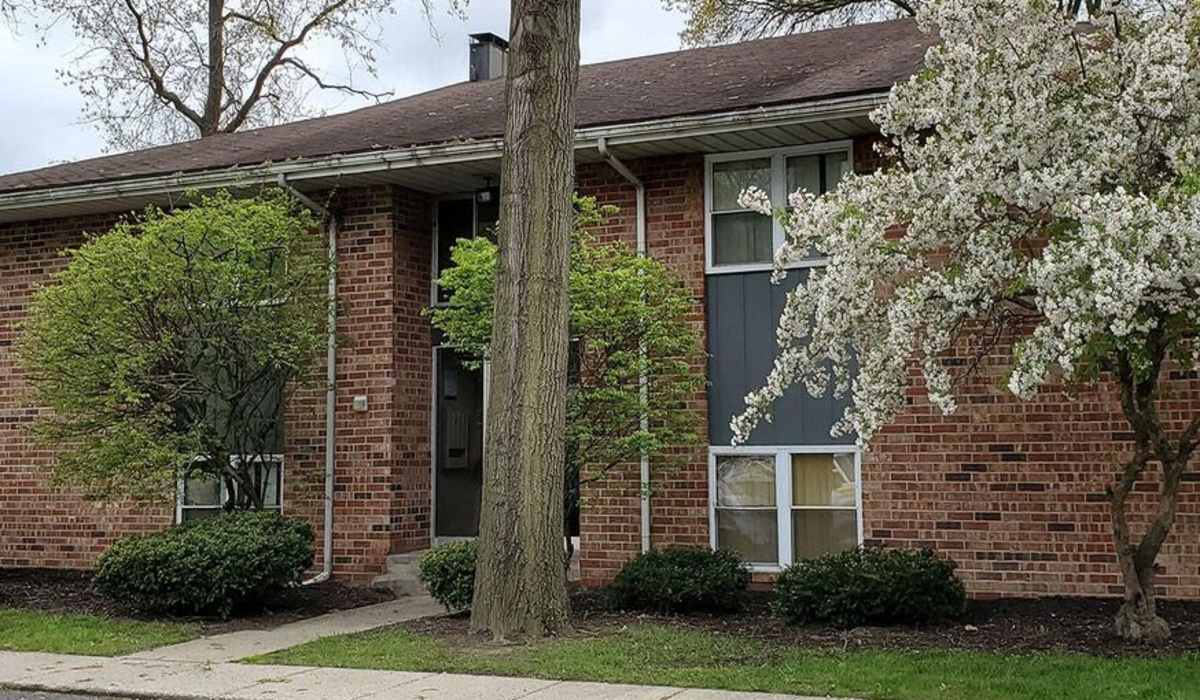 Charming brick exterior with lush landscaping and flowering trees at The Reserve at Pin Oak Manor Apartments in Mishawaka, Indiana.