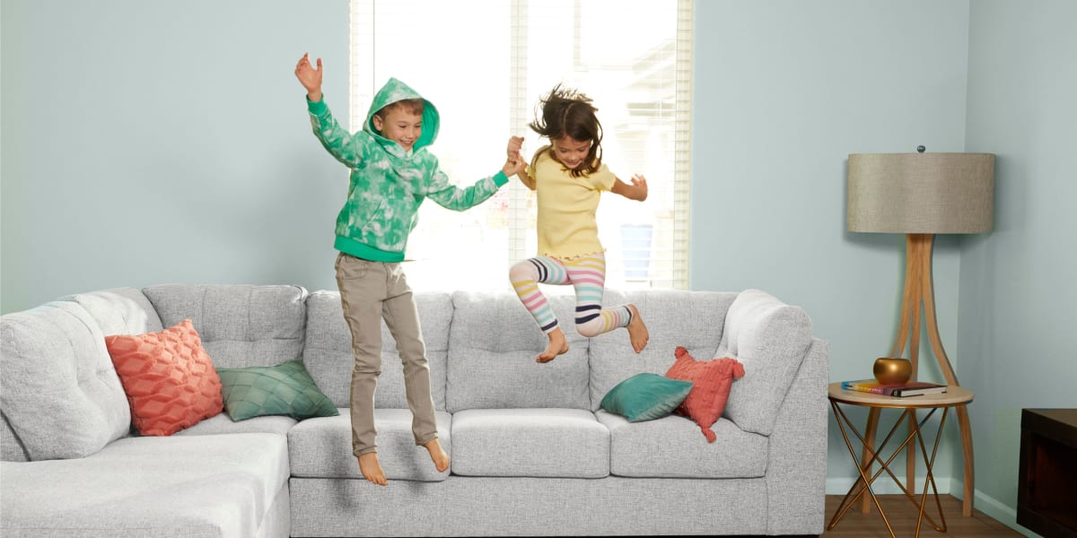 Two kids jumping off a couch at BB Living at Union Park in Phoenix, Arizona