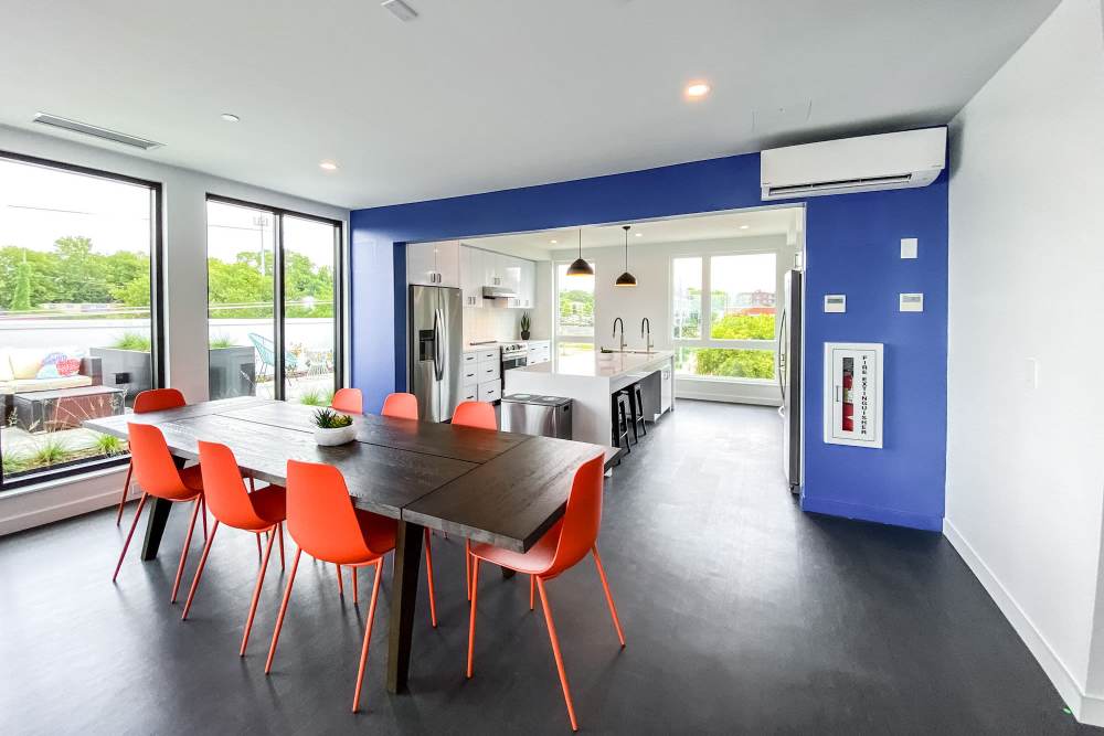 Community kitchen with island, stools, refrigerator and dining area at Martin Flats in Nashville, Tennessee