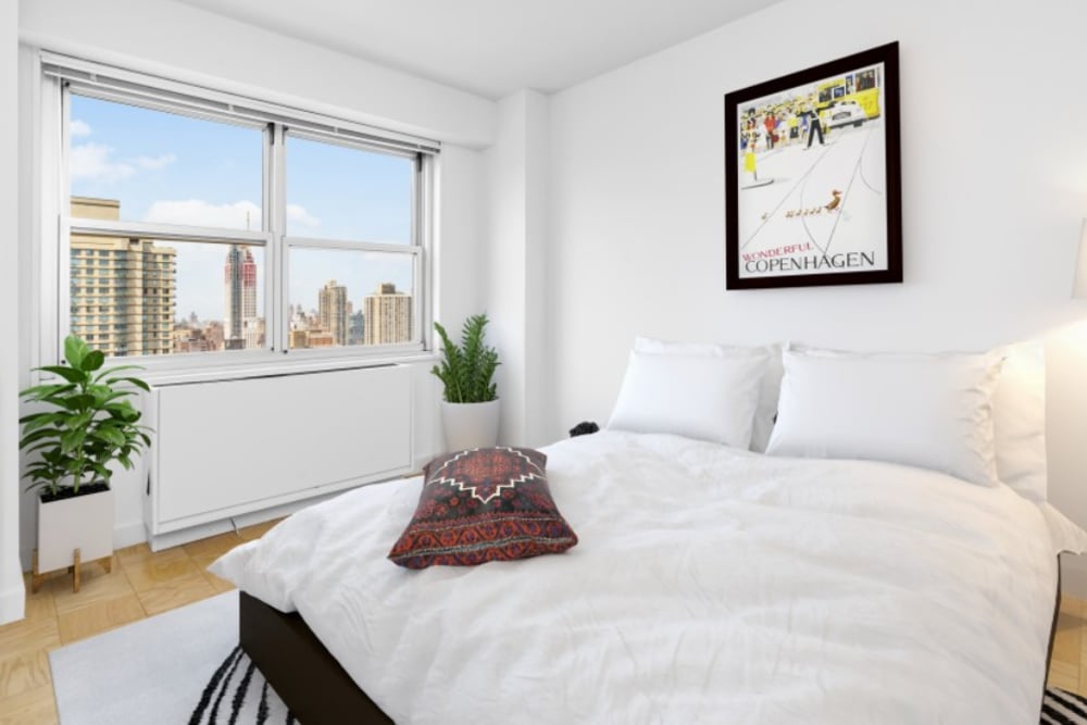 Model bedroom with skyline views out the window at The Caldwell in New York, New York