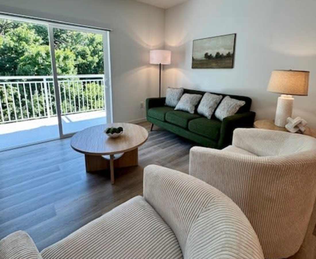 Sofa with decorative pillows and lamp with access to patio at Pritchard Park Place in Racine, Wisconsin