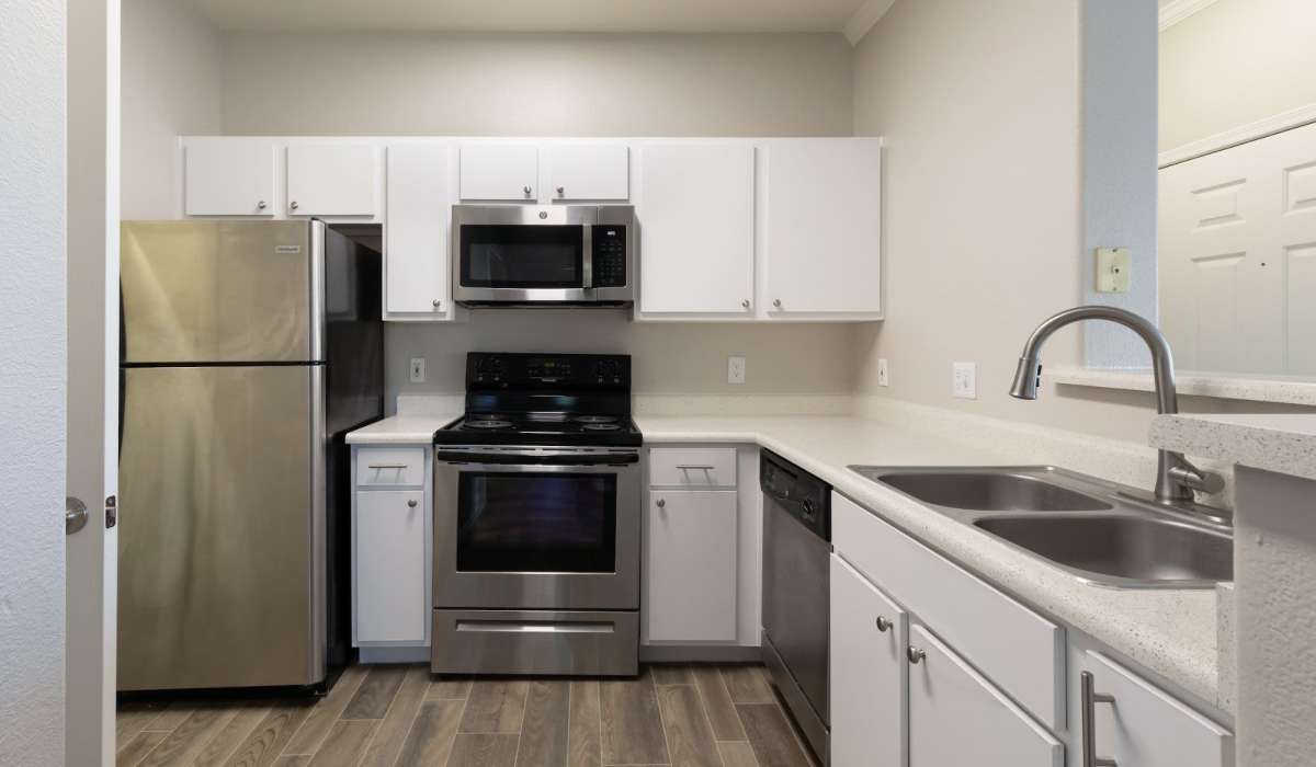 Ultra-modern kitchen with an island, quartz countertops, and custom wood cabinetry in a model apartment at Sol District in Phoenix, Arizona