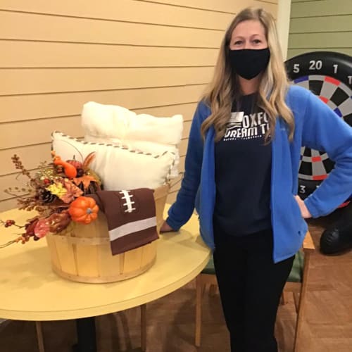 A team member standing next to a gift basket at Oxford Glen Memory Care at Owasso in Owasso, Oklahoma