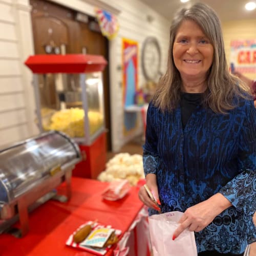 Resident serving herself some theater food at Oxford Glen Memory Care at Carrollton in Carrollton, Texas