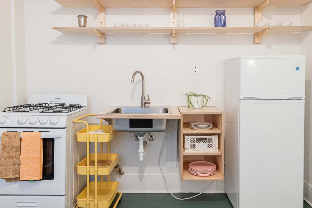 Compact apartment kitchen with a white refrigerator, stove and sink at Detroit Living in Detroit,Michigan