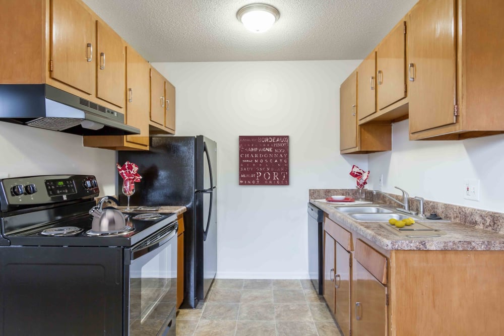 Kitchen with black appliances and maple cabinets at Penfield Village Apartments in Penfield, New York