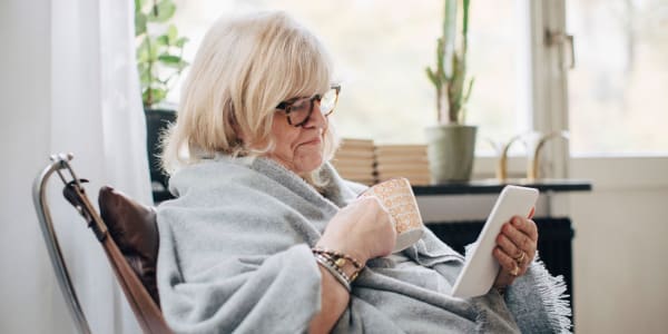 Resident wrapped in a blanked drinking coffee and looking at her smart phone at Ingleside Communities in Mount Horeb, Wisconsin