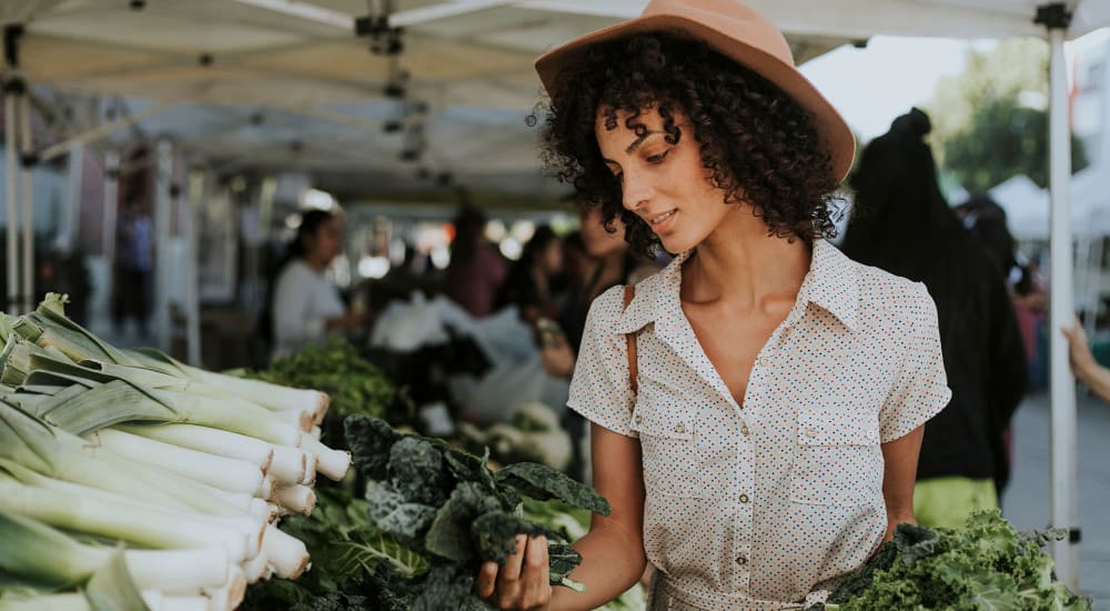 Resident woman shopping in a farmer's market looking at vegetables near Quailwood Apartments in Stockton, California