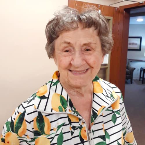 Smiling resident in a floral zip-up sweater at The Oxford Grand Assisted Living & Memory Care in McKinney, Texas