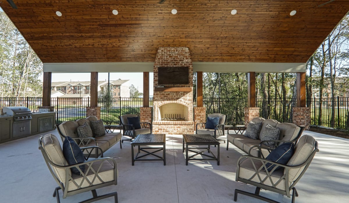 Poolside patio with tables chairs and outdoor fireplace at La Maison Of Saraland in Saraland, Alabama