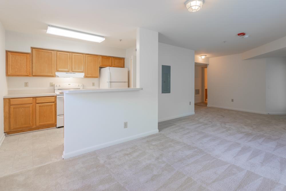Unfurnished living room with view to kitchen at Corrigan Square Apartments in Gaithersburg, Maryland