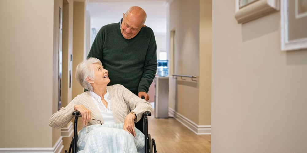 Elderly man pushing wife in wheelchair at Vista Prairie at Monarch Meadows in North Mankato, Minnesota