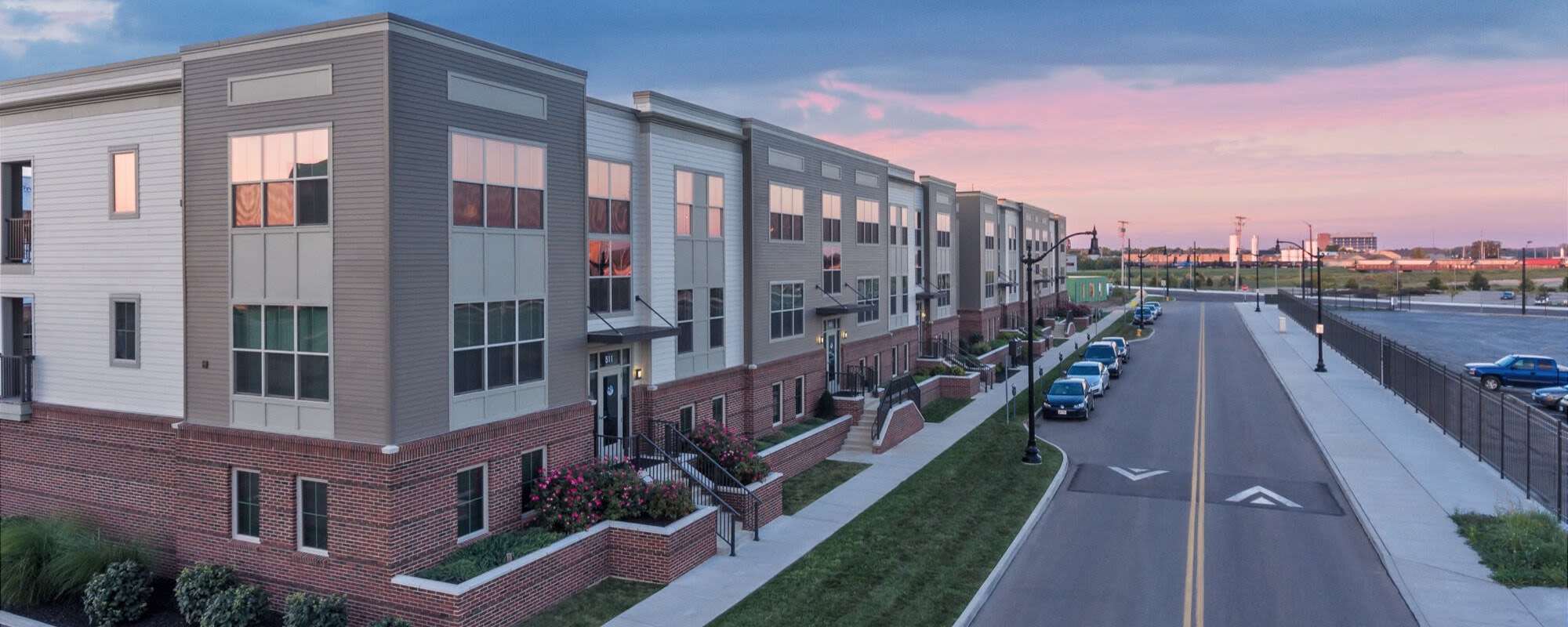 Modern apartment community with landscaped gardens, brick exteriors, and ample parking along the street at Water Street Apartments in Dayton, Ohio