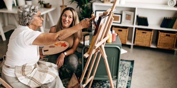 Resident painting on canvas while a caretaker stands by at a WISH community