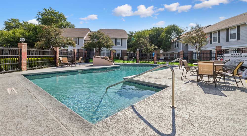 Sparkling swimming pool with lounge chairs at Arbors of Taylor in Taylor, Texas