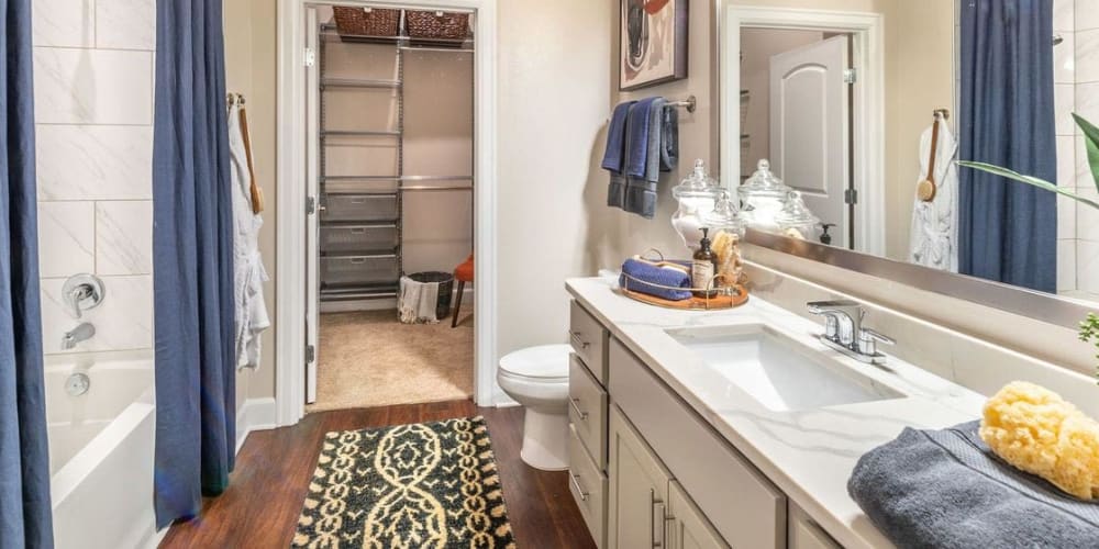 Model bathroom with granite countertops and walk-in closet at Switchyard in Carrollton, Texas