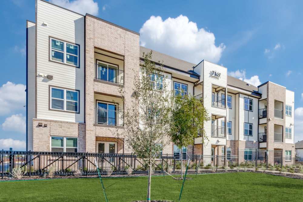 Apartments with lush green lawn at The Trail Lakes in Fort Worth, Texas
