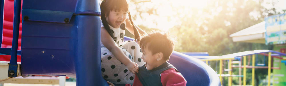 Two children playing on a slide in a park near Briarcliff Apartment Homes in Milledgeville, Georgia