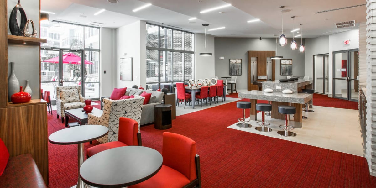 Large colorful community room with dining, kitchen, pool, and sitting areas at Marq Midtown 205 in Charlotte, North Carolina