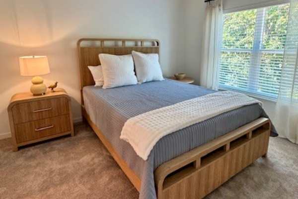 Wooden bed frame with gray bedding at Pritchard Park Place in Racine, Wisconsin