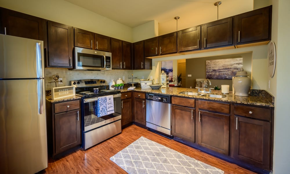 Kitchen with dark wood cabinets and wood style flooring at Pecan Springs Apartments in San Antonio, Texas