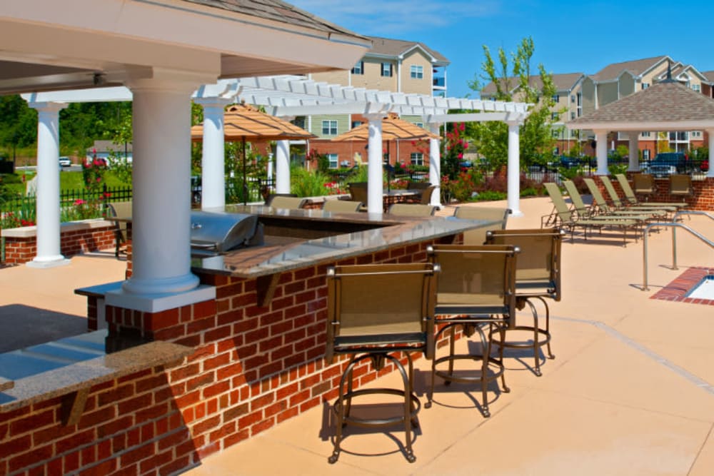 A barbeque area with bar seating next to the pool at Meridian Watermark in North Chesterfield, Virginia