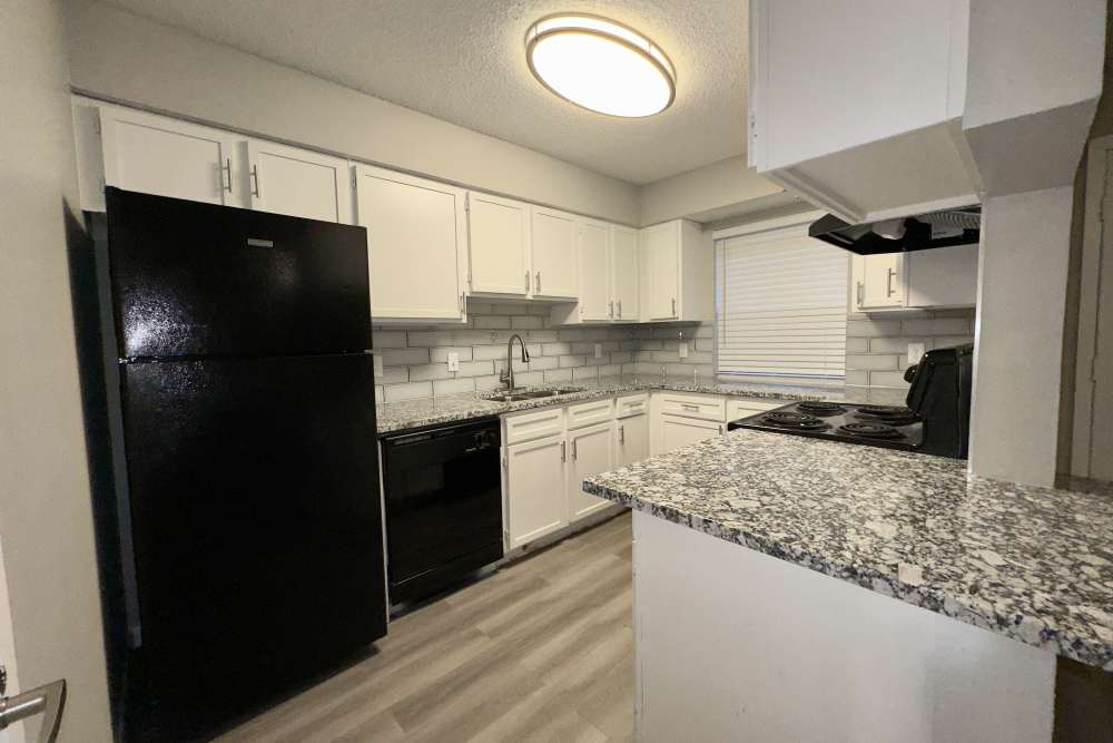 Kitchen with black appilances and granite countertop at Villa De Oro in San Antonio, Texas