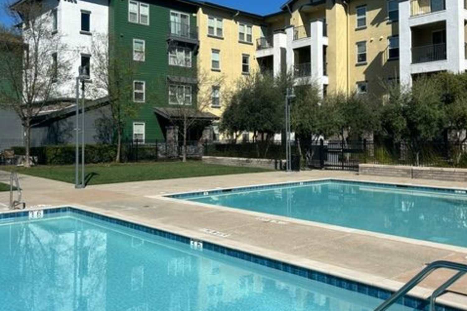 Dual pools with lounge chairs and view of apartments at Oak Grove at Dublin Ranch in Dublin, California