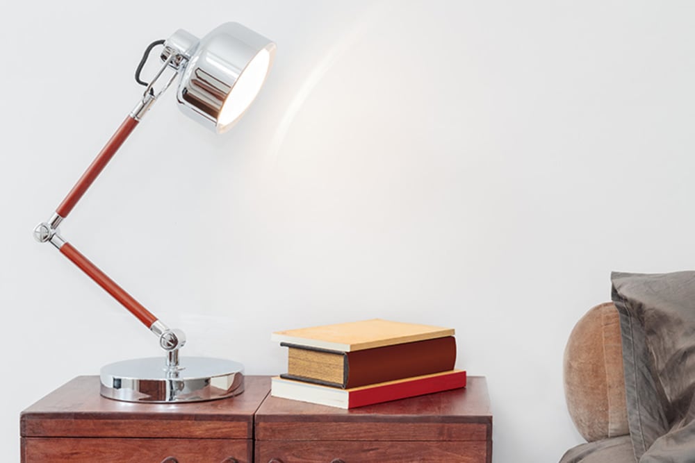 Lamp, nightstand, and bed in Pacific Shores luxury apartment bedroom