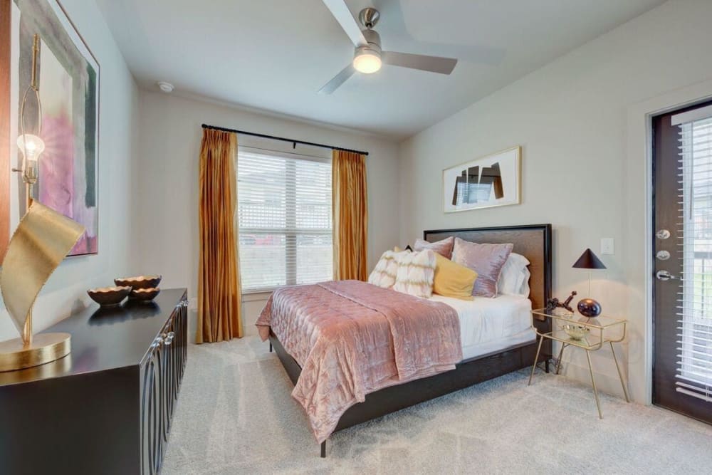 Model bedroom with large windows and ceiling fan at Palmetto Pointe in San Antonio, Texas