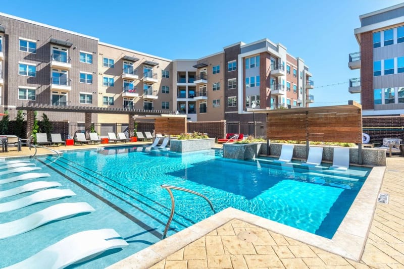 Resort-style swimming pool flanked by chaise lounge chairs at Switchyard in Carrollton, Texas