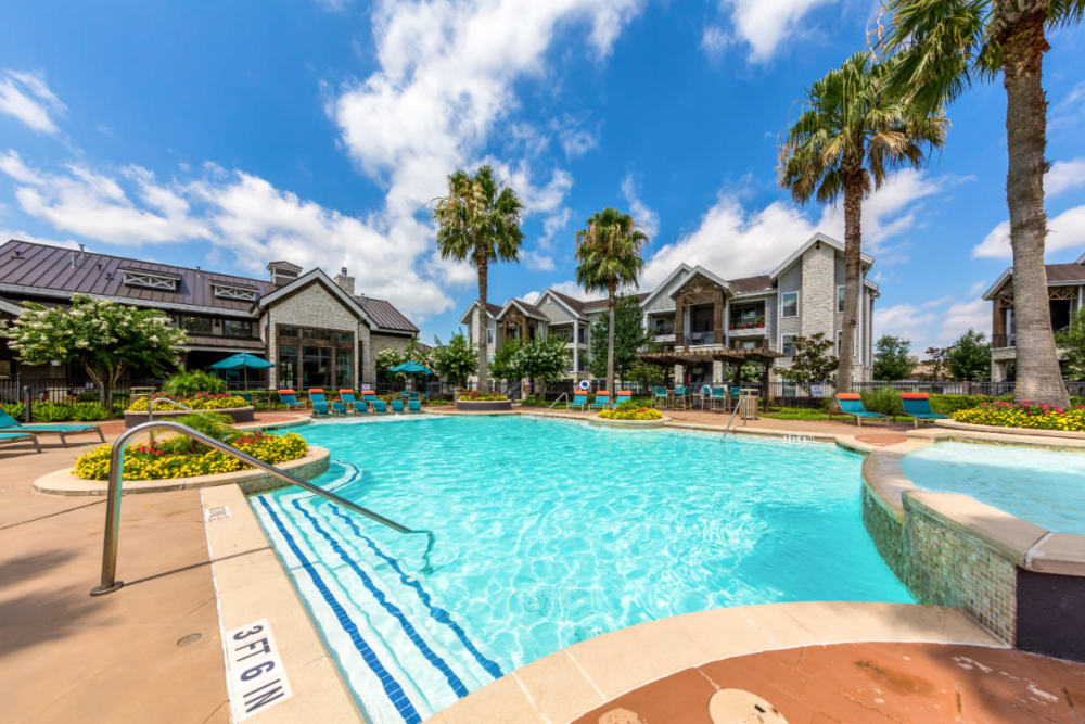 Resort style swimming pool surrounded by lounge chairs at Marquis at Sugar Land in Sugar Land, Texas