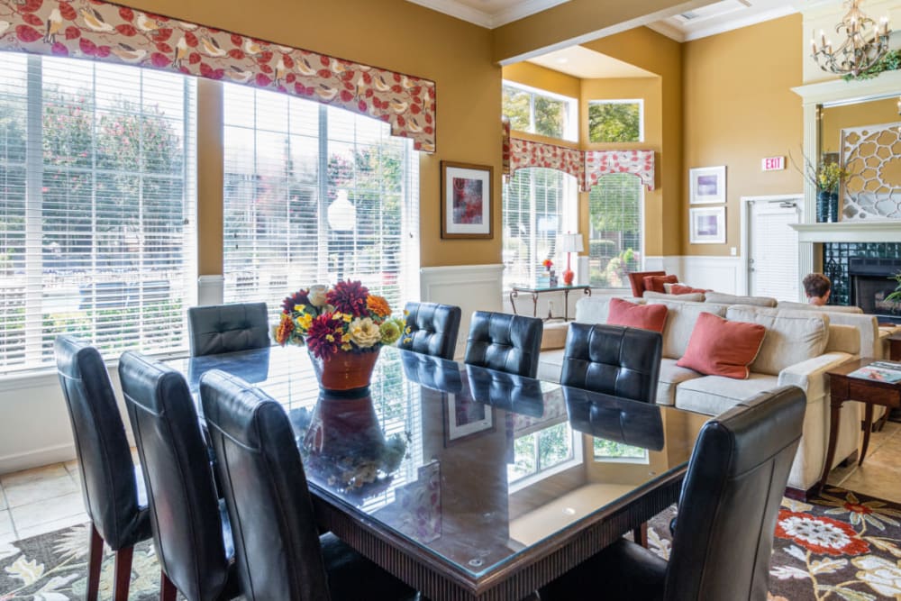 Community clubhouse sitting area with dining table and chairs, sofas, and large windows at Marquis of Carmel Valley in Charlotte, North Carolina