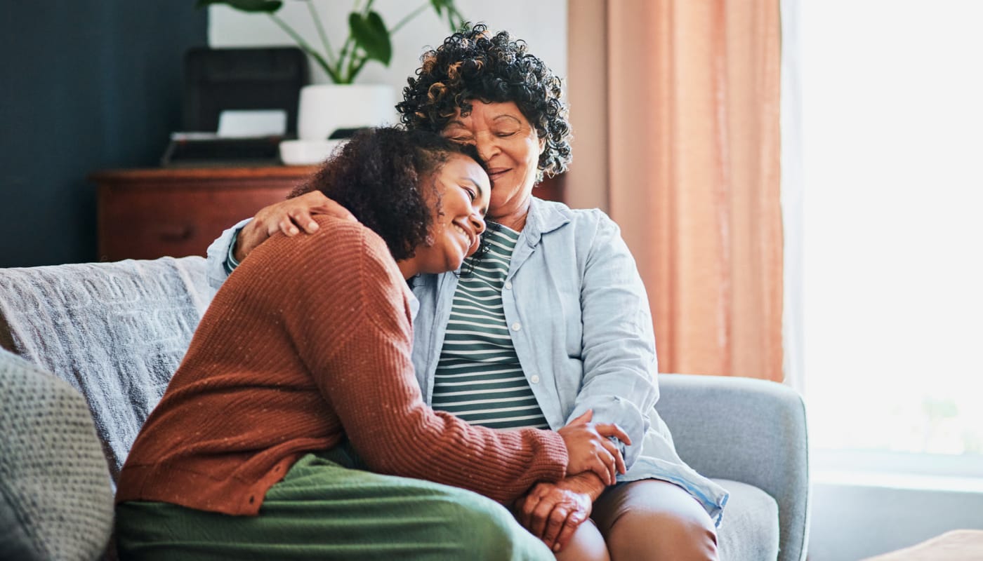 Resident and caregiver hugging on the couch in their apartment at The Pillars of Hermantown in Hermantown, Minnesota