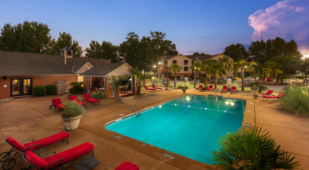 Beautiful view of the community with buildings and swimming pool with multiple lounge chairs at The Arbors On Taylor in Montgomery, Alabama