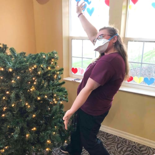 Team member posing next to a christmas tree at The Oxford Grand Assisted Living & Memory Care in Wichita, Kansas
