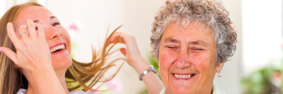 Resident and caregiver laughing together at Geneva Lake Manor in Lake Geneva, Wisconsin