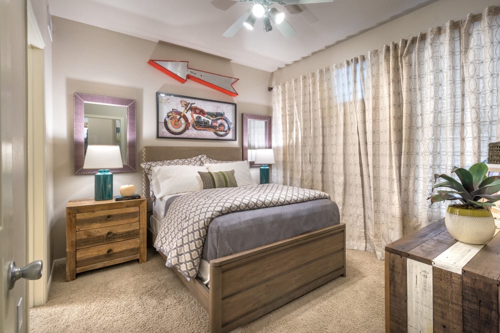 Model bedroom with plush carpeting and a ceiling fan at 75 West in Dallas, Texas