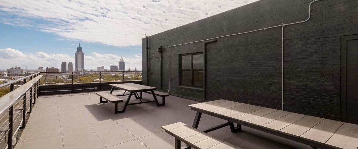 Rooftop deck with picnic tables and view of city skyline at The Gateway Apartments in Mobile, Alabama