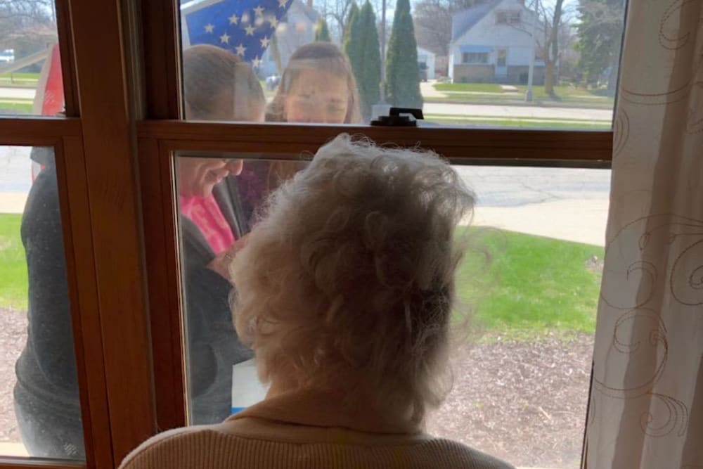 Resident watches through window as flag is raised at Ramsey Woods in Cudahy, Wisconsin.