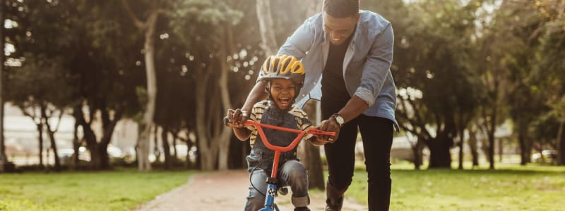 Dad pushing his son through the local park near Eastgold Westchester in Dobbs Ferry, New York