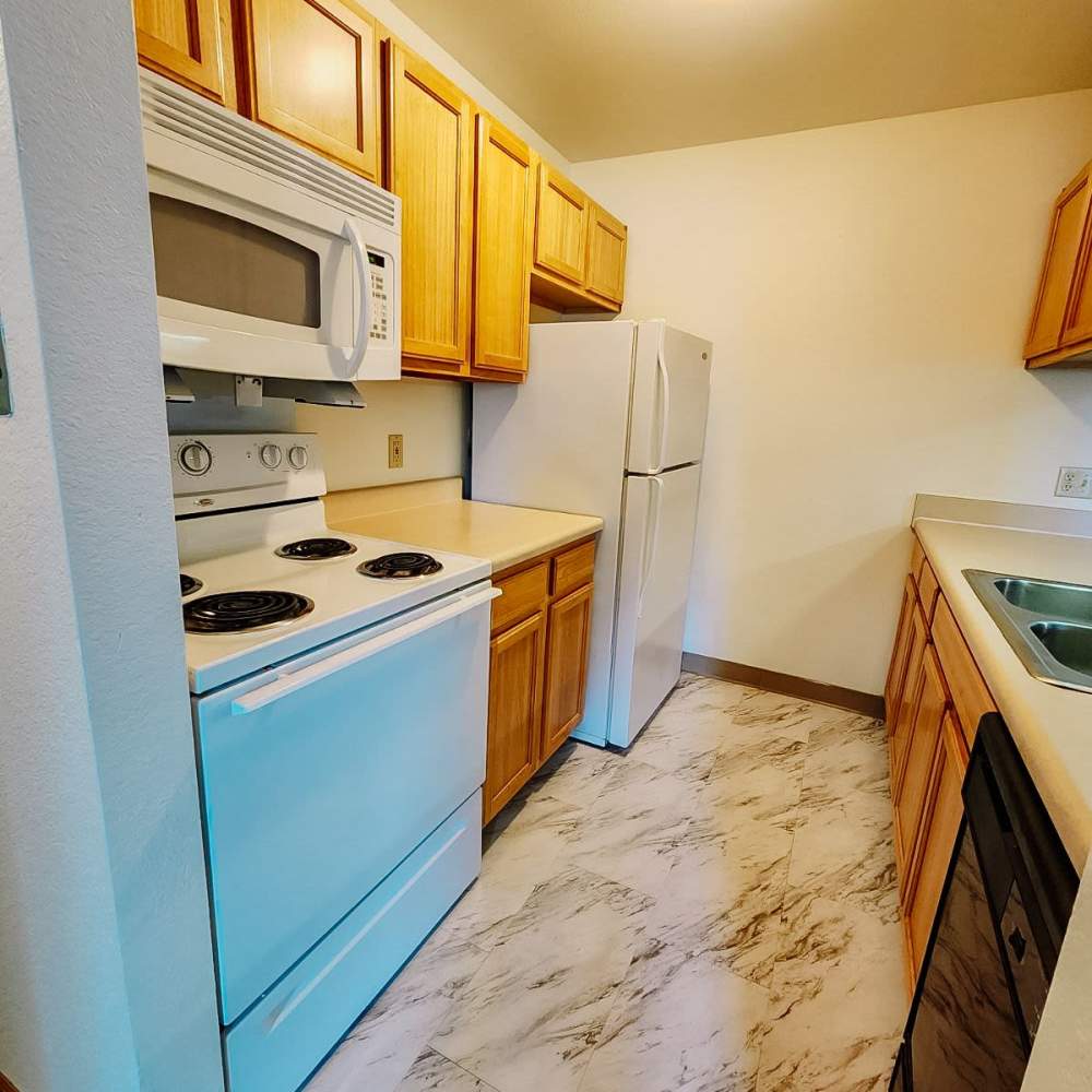 Kitchen with refrigerator and wooden cabinets at Rivercrest Apartments in Croswell, Michigan