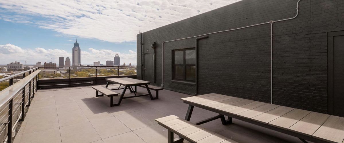 Rooftop deck with picnic tables and city skyline in back at The Gateway Apartments in Mobile, Alabama