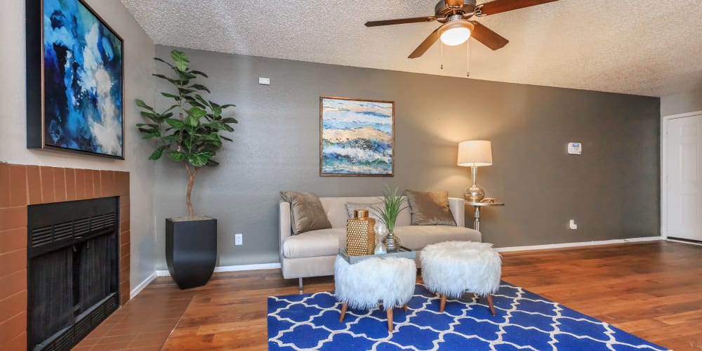 Living room with a fireplace and ceiling fan at Tides at Highland Meadows in Dallas, Texas