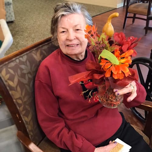 Resident with a festive plant arrangement at Oxford Glen Memory Care at Grand Prairie in Grand Prairie, Texas