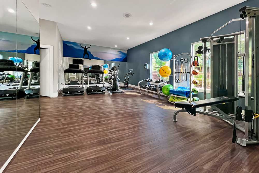 Fitness room with cardio machines and free weights at Newport Crossing Apartments in Newcastle, Washington
