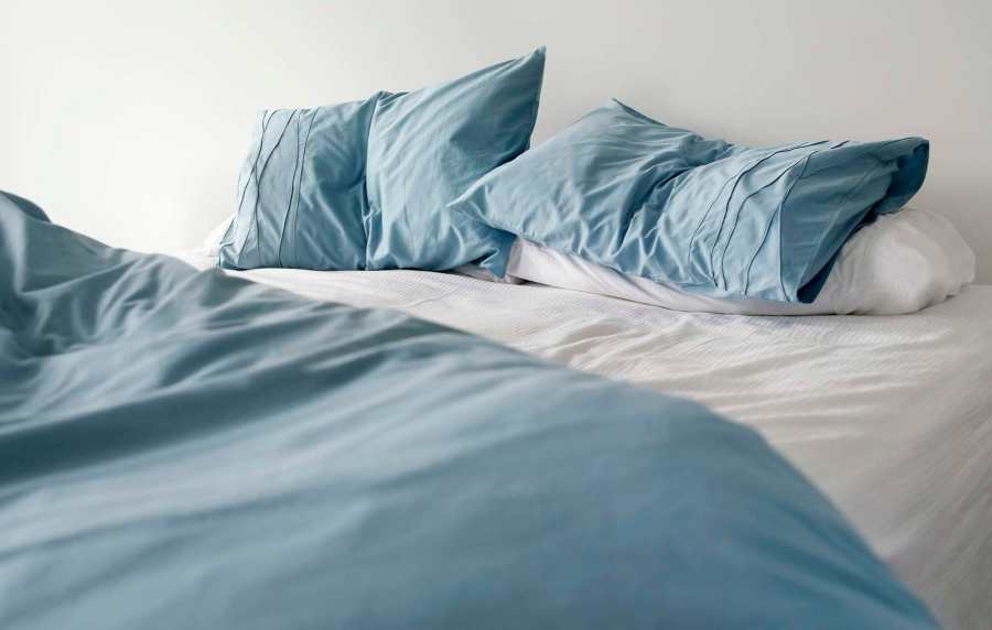 Cozy bed with soft blue pillows and fresh linens at Standard at Royal Lane in Dallas, Texas