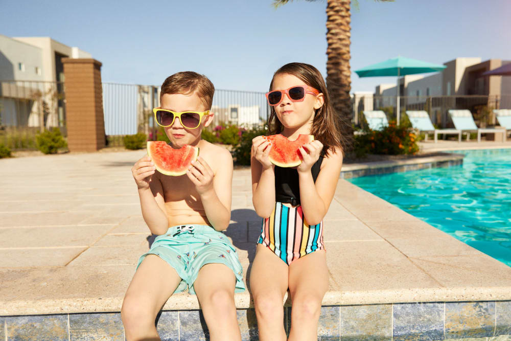 Two kids eating watermelon by the pool at BB Living at Civic Square in Goodyear, Arizona