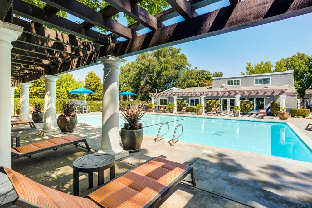 Swimming pool with a sundeck and orange lounge chairs at The Woodlands Apartments in Sacramento, California
