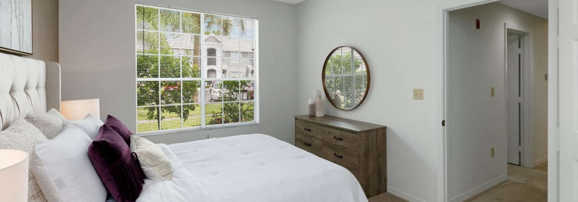 Bedroom with a bed and large windows at Woodmere Apartments of Venice in Venice, Florida